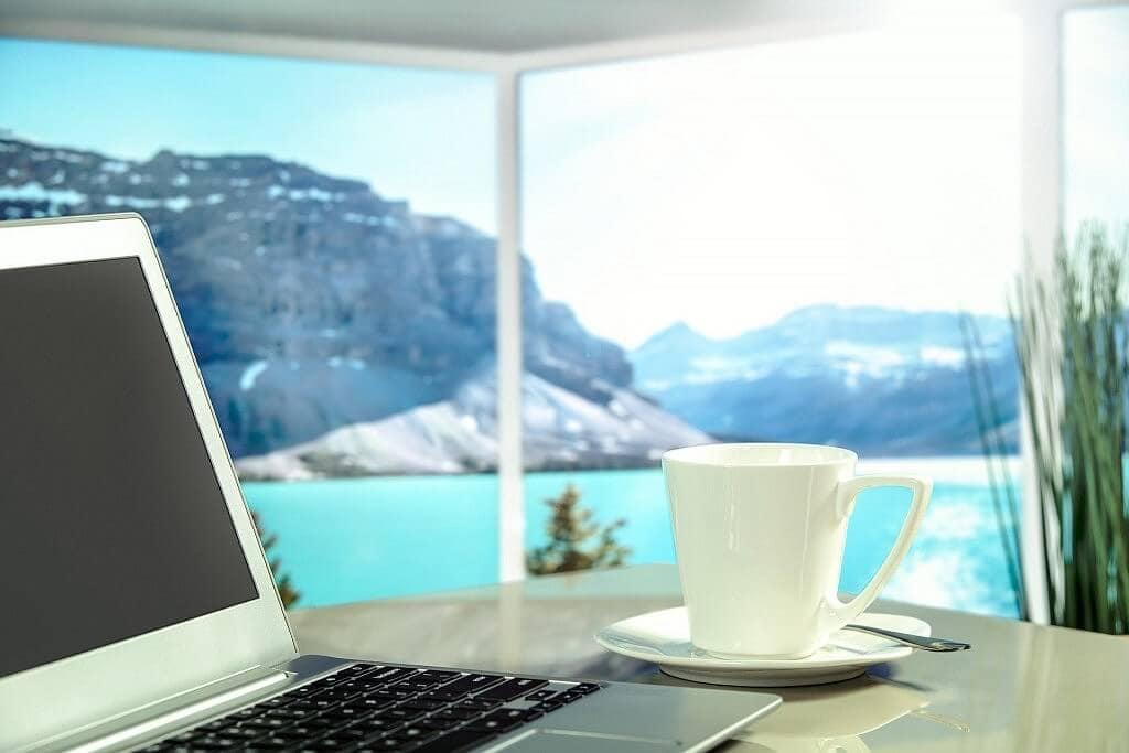 A laptop and a cup of coffee in with beautiful view